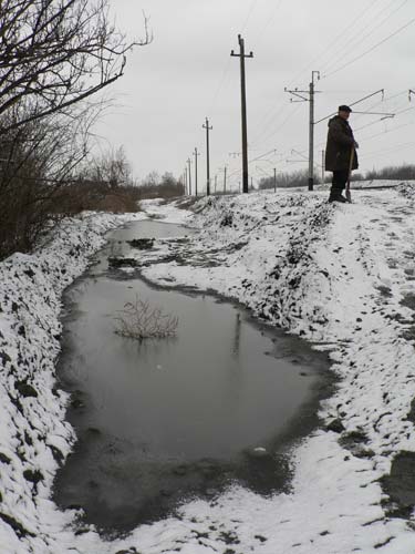 Еще не полностью растаял снег, и не было сильных дождей, но огороды двух домов по улице Белгородской уже заливает вода. Местный житель Геннадий Поляков, работающий по договору от Центра занятости, делает насыпь, чтобы остановить воду